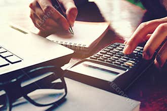 Close up woman hand using calculator and writing make note with