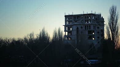 A flock of crows flying over the ruins of the building. dusk. sunset