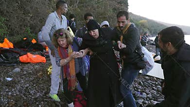 LESVOS, GREECE - NOV 5, 2015: Volunteers help refugee woman to go on shore.