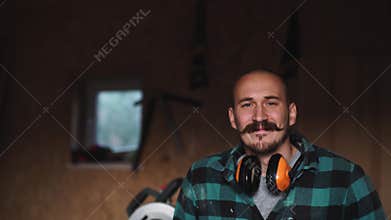 Portrait of a bold worker carpenter with vintage moustache in work clothes in front of workbench tools