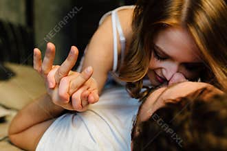 Young couple in love lying in bed in hotel, embracing on white sheets, close up