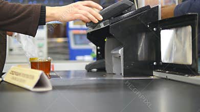 Shopper paying for products at checkout. Foods on conveyor belt at the supermarket. Cash desk with cashier and terminal