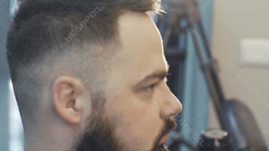Female haircutter drying male hair. Slowly