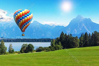 Scenic summer landscape with hot air balloon, lake and mountains