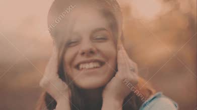 Close-up portrait of a beautiful young girl with long dark hair wearing straw hat. She plays with her hair in the warm