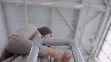 Rear view of wealthy woman with luggage walking towards private jet at airport terminal with tablet pc