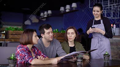 Three friends ordering food in restaurant