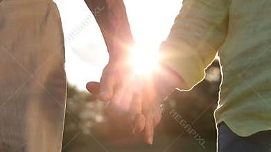 Romantic senior couple holding hands at sunset