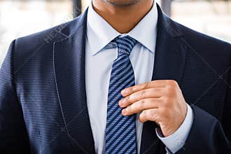 Elegant businessman in suit tying necktie