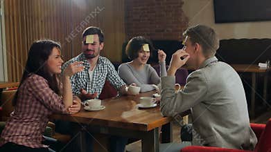 Four friends are playing together who I am in cafe