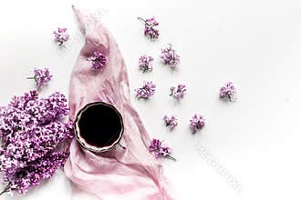 Work place with lilic flowers, coffee and scarf for woman on white desk background top view mock-up
