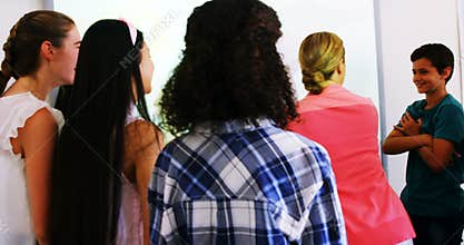 Teacher and students discussing over world map on whiteboard in classroom