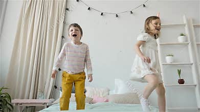 Portrait of children jumping on a bed, little boy and girl brother and sister have fun and laughing