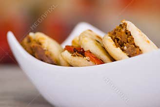 Close up of a traditional delicious arepas, shredded chicken avocado and cheddar cheese and shredded beef on wooden