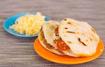 Traditional delicious arepas, shredded chicken avocado and cheddar cheese and shredded beef with grated cheese on wooden
