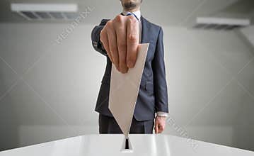 Election and democracy concept. Voter holds envelope or paper in hand above ballot