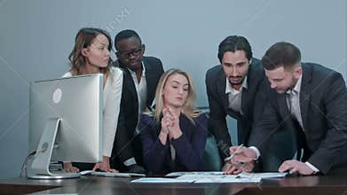 Group of multiethnic diverse young business people in a meeting standing around a table with serious expressions