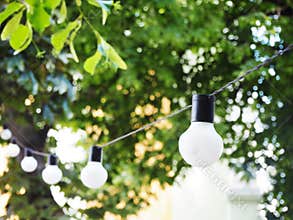String of light bulbs. Birthday or summer garden party decoration. Modern blurred background with bokeh lights and