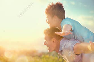 Happy father and son having fun over beautiful sky outdoors