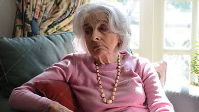 Lonely Senior Woman Sitting In Armchair At Home