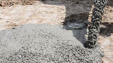 Construction workers pour concrete mix from cement mixer