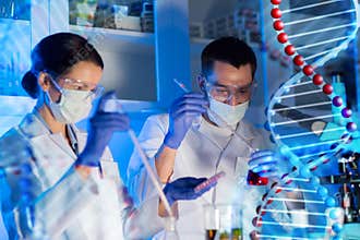 Scientists with pipettes and test tubes in lab