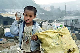 Poor Filipino boy gathering plastic on landfill