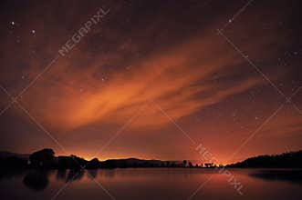 Beautiful night sky with stars, clouds and reflections in the wa