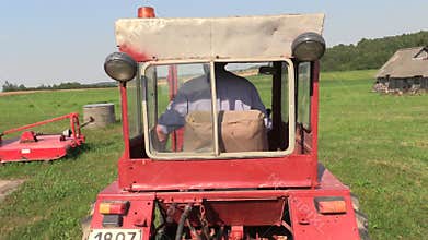 Farmer drive an old red tractor through meadow
