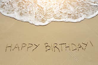 Happy birthday written on sand beach