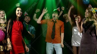 Happy group of friends dancing at a nightclub and