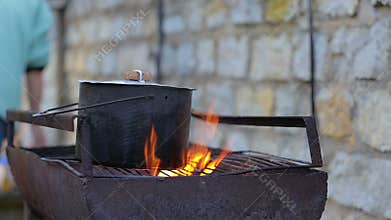 Cooking soup on fire in grill.