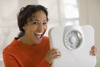 Happy black woman holding scale