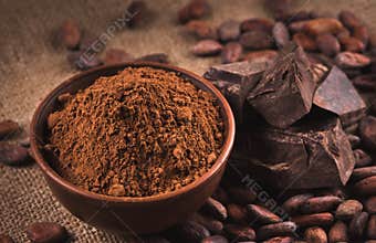 Raw cocoa beans, clay bowl with cocoa powder, chocolate on sack