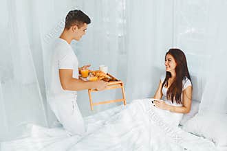 Man bringing woman breakfast in bed