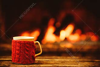 Cup of hot drink in front of warm fireplace. Holiday Christmas c