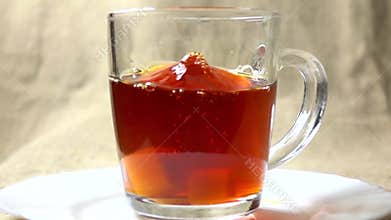 Super slow motion video of two sugar cubes falling into glass cup of black tea