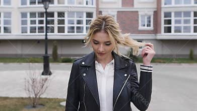 Beautiful blonde walking on the sidewalk around the stylish home. She is a young