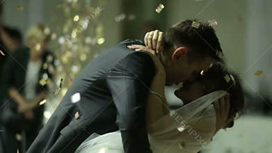 Beautiful brunette bride and handsome groom dancing first dance at the wedding party shrouded by confetti. Very tender