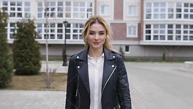 Beautiful blonde walking on the sidewalk around the stylish home. She is a young