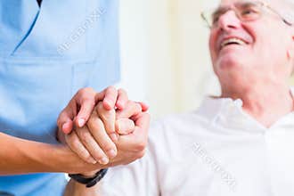 Nurse holding hand of senior man in rest home