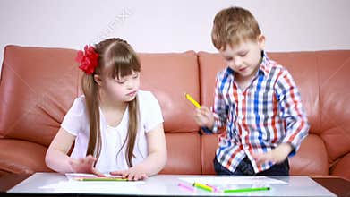 Two adorable happy children drawing with crayons at playschool. girl with Down syndrome. rehabilitation of the disabled