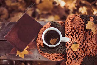Hot coffee and red book with autumn leaves on wood background - seasonal relax concept