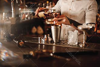Bartender is adding ingredient in shaker at bar counter
