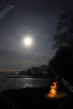 Bonfire flame and moon over lake