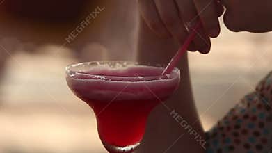 Woman drinking red cocktail at the sunset