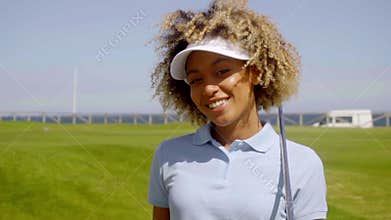 Cheerful female golfer walking with golf club
