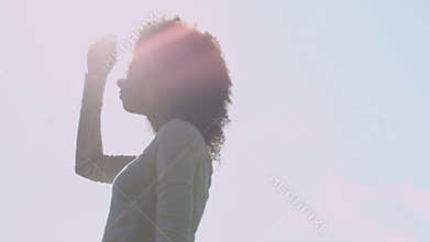 Young beautiful mixed race woman with curly afro hair smiling happily in a green park.