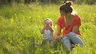 Beautiful mother playing with her little daughter in the park, Blow dandelion
