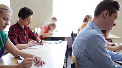 Students with notebooks writing test at school